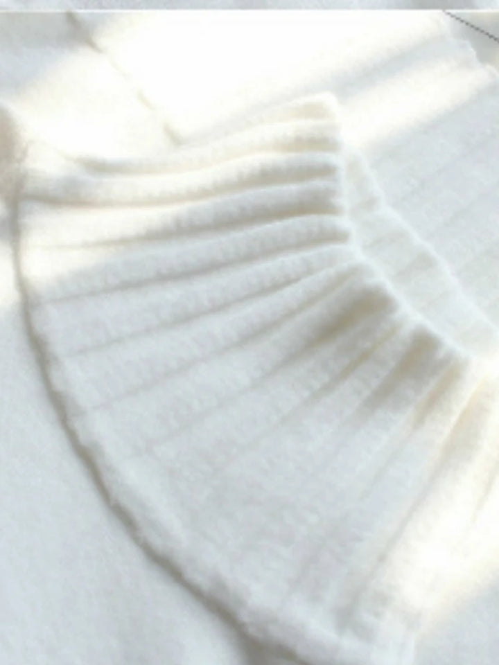 Close-up of a white sweater with ribbed texture on a light background