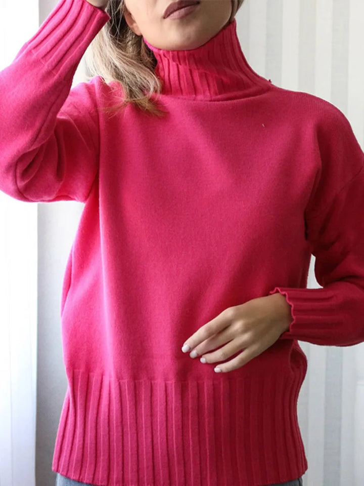 Person wearing a bright pink turtleneck sweater against a white background