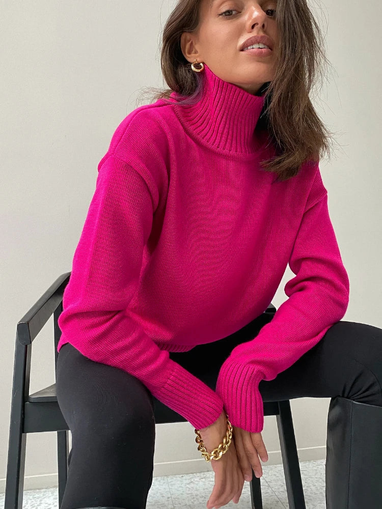 Woman wearing a bright pink sweater sitting on a chair.
